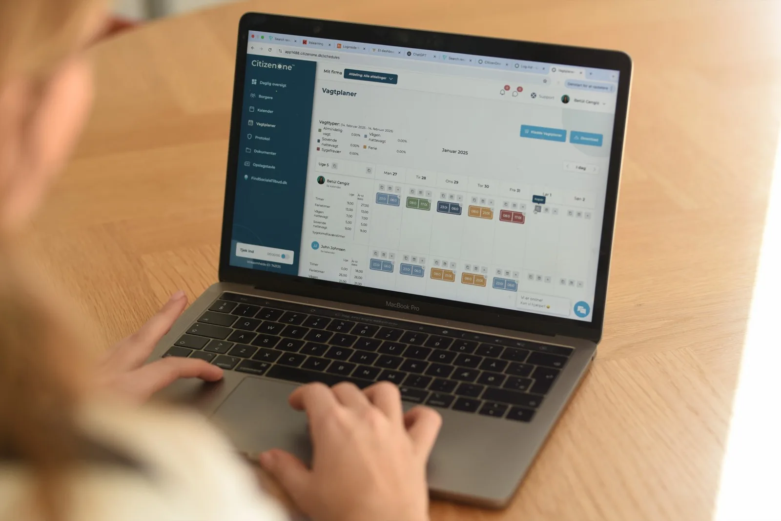 A staff member working in CitizenOne's shift schedule on a laptop.