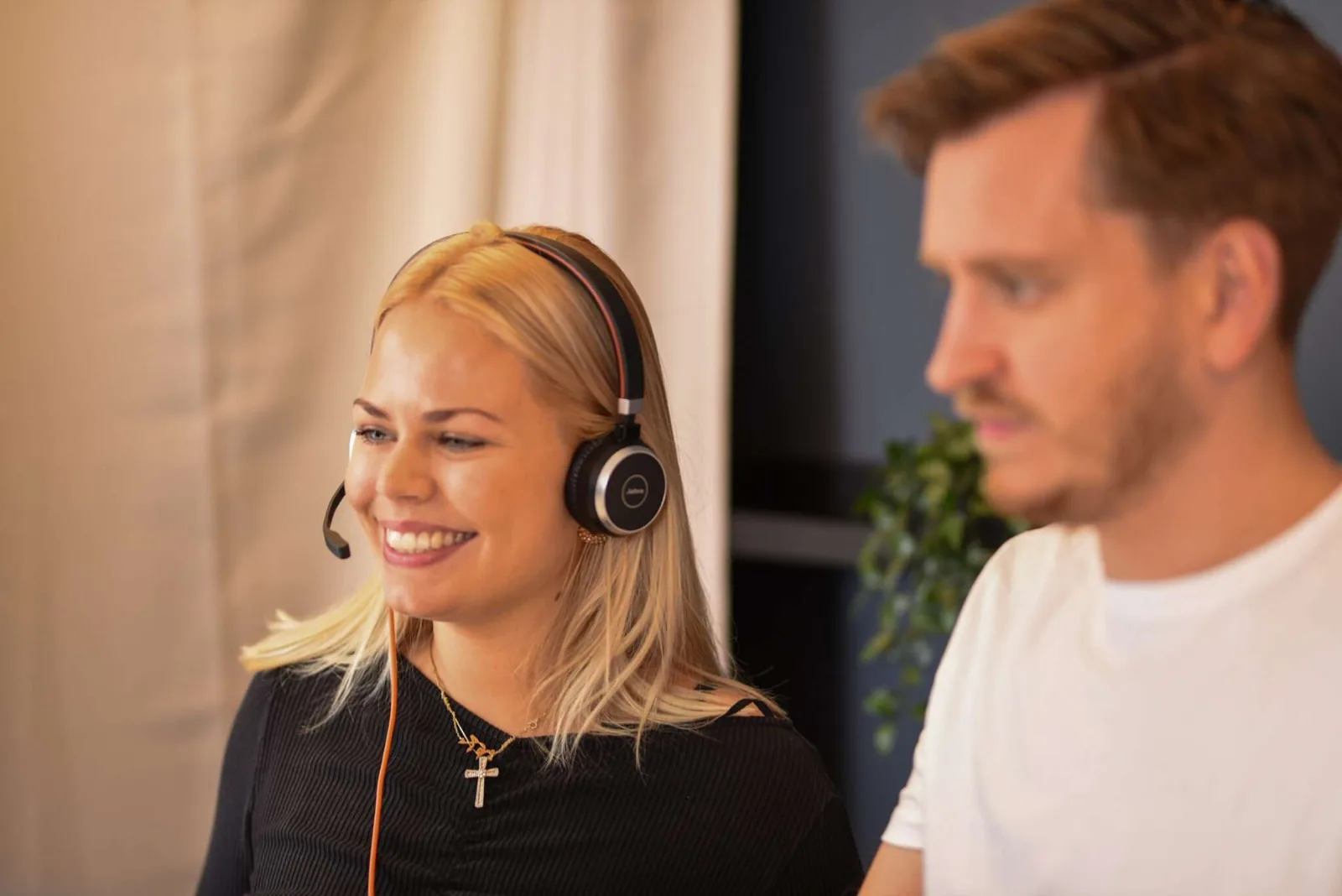Two CitizenOne staff members, the one in front wearing a headset, in a conversation with a customer.